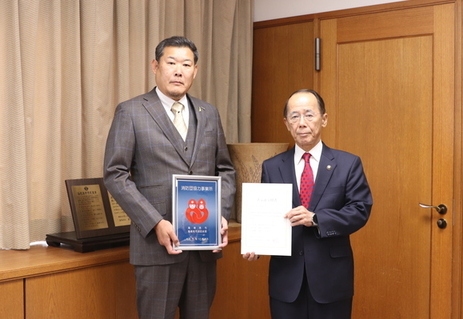 海老名市消防団協力事業所表示証を持った見上氏と内野市長が2人で写っている写真