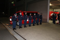第6次派遣隊の消防隊員が出発する消防車両の前で整列している写真