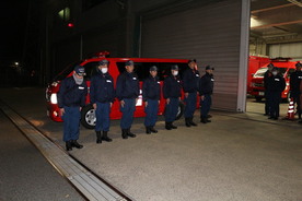 出発する消防車両の前で整列している写真